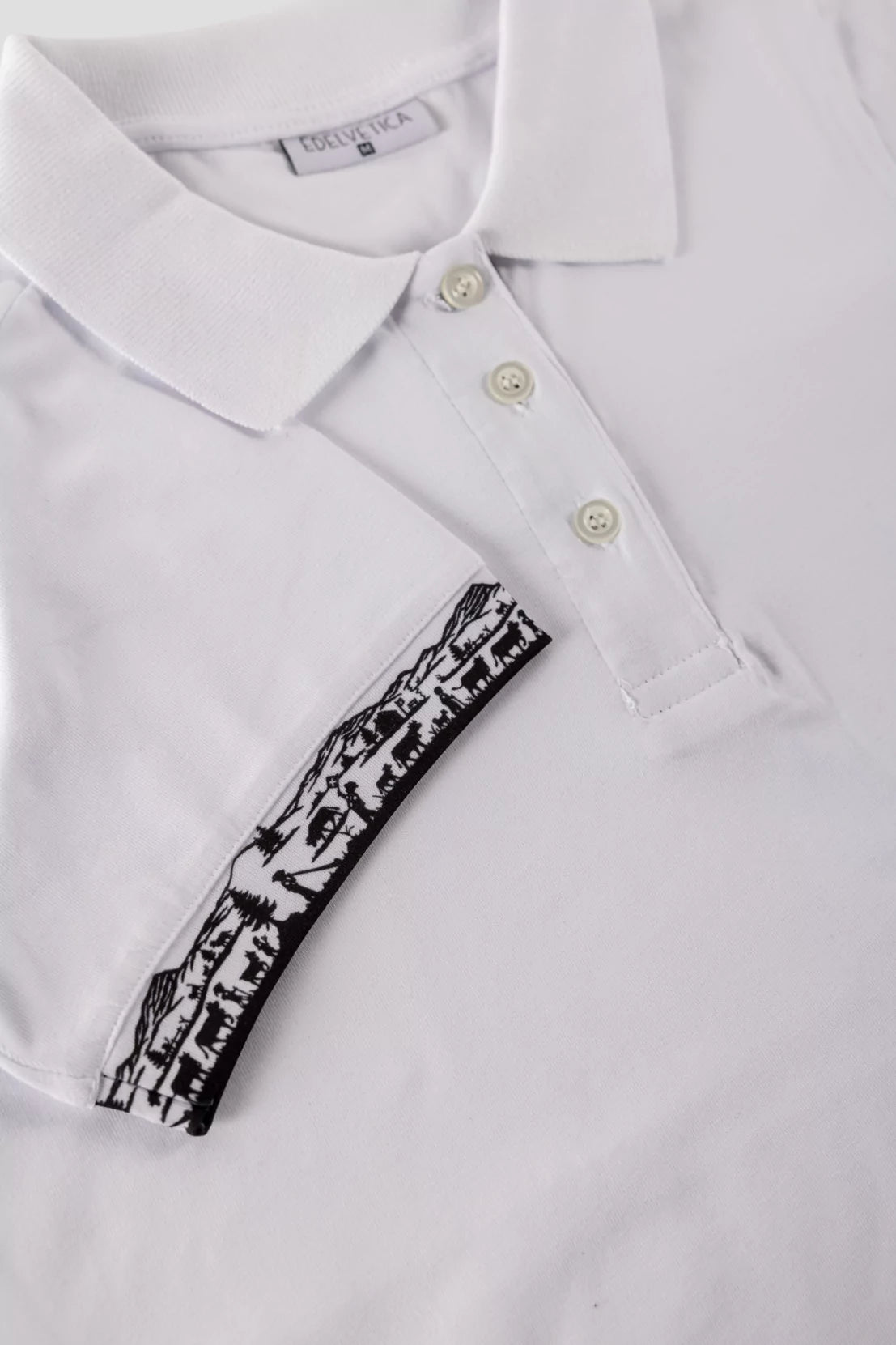 Damen Scherenschnitt Polo-Shirt von Edelvetica, gekennzeichnet durch einzigartige Scherenschnitt-Details am Kragen und den Armabschlüssen. Dieses elegante Polo-Shirt verbindet traditionelle Schweizer Kunst mit modernem Stil und bietet eine stilvolle Option für diverse Anlässe. Perfekt für eine anspruchsvolle Garderobe, die traditionelle Elemente und zeitgenössische Mode vereint.