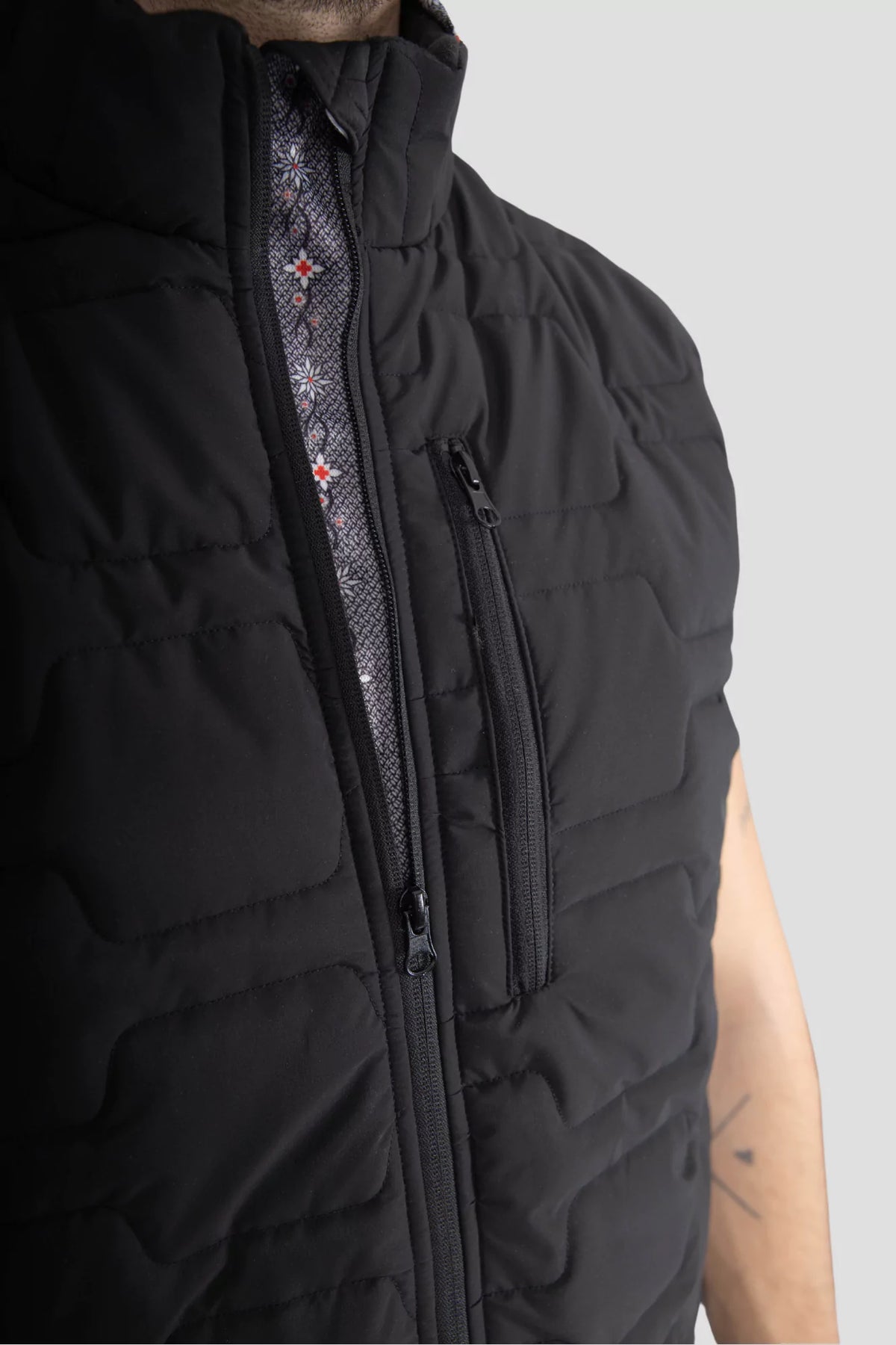 Gilet Edelweiss Herren in Schwarz mit grauem Edelweiss-Muster, hochwertig verarbeitet, mit dezenten Edelweiss-Streifen am Reissverschluss und Nacken, ideal für Arbeit, Freizeit und elegante Anlässe.